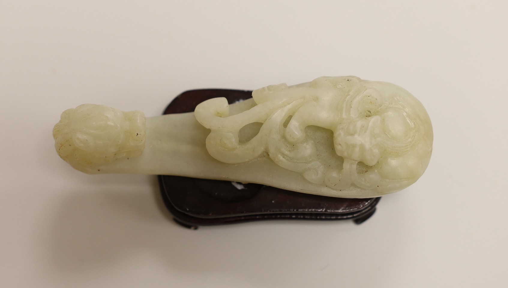 A Chinese pale celadon and grey jade mythical beast on stand and a pale celadon jade belt hook, mythical beast 11cms wide